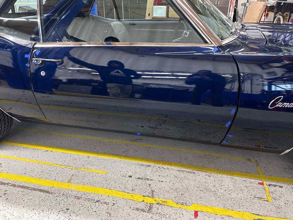 A blue car is parked in a garage next to a yellow line.