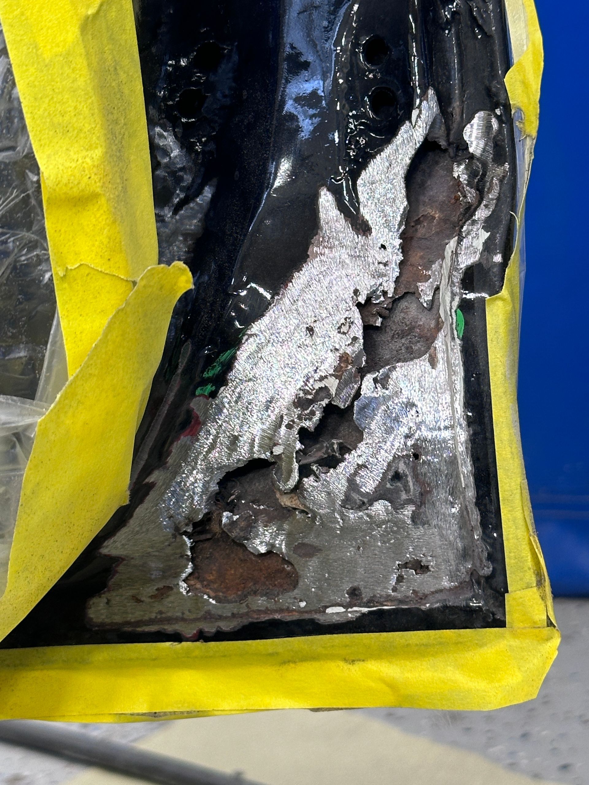 A piece of metal is covered in yellow tape.