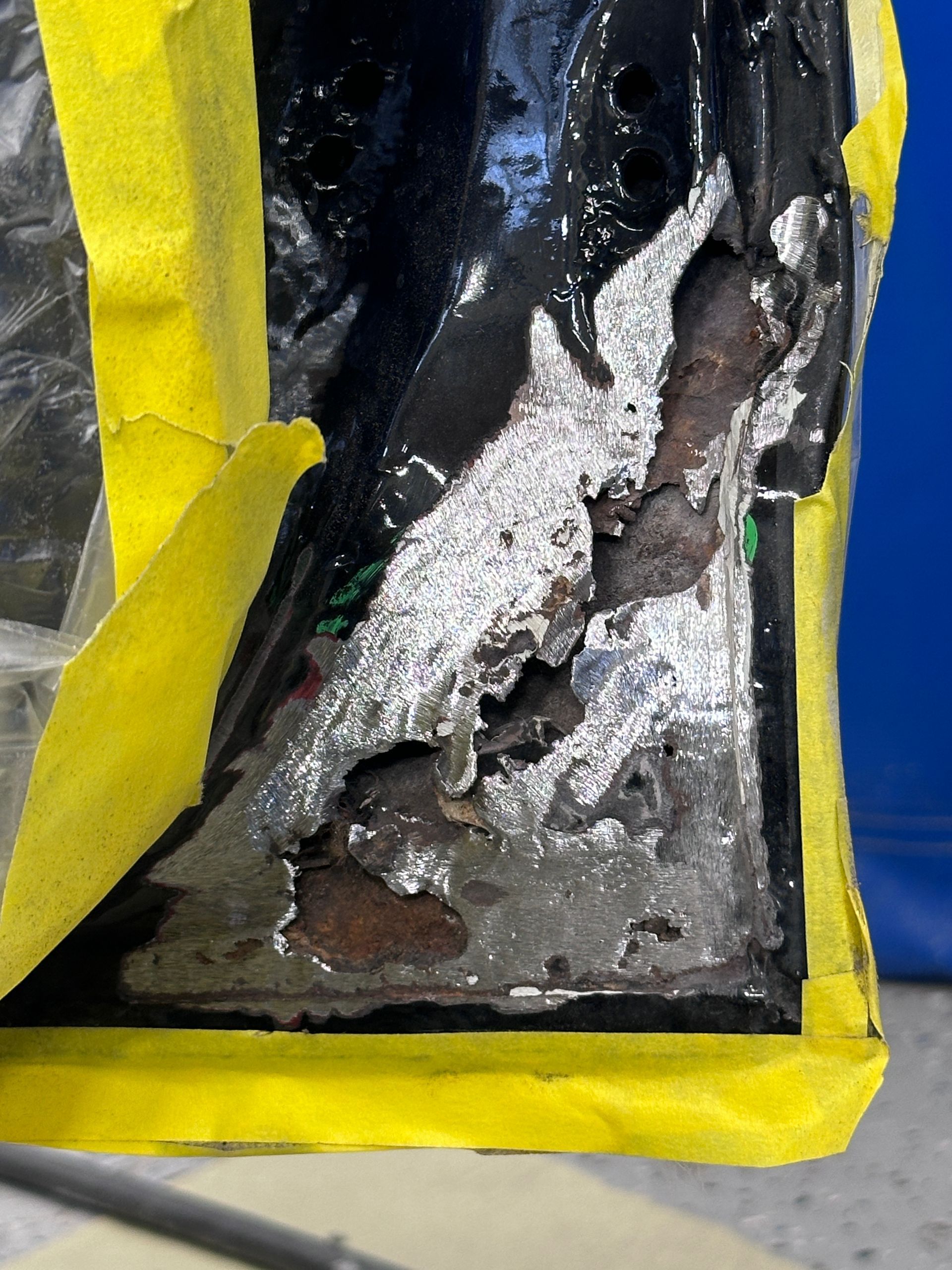 A piece of metal is covered in yellow tape.