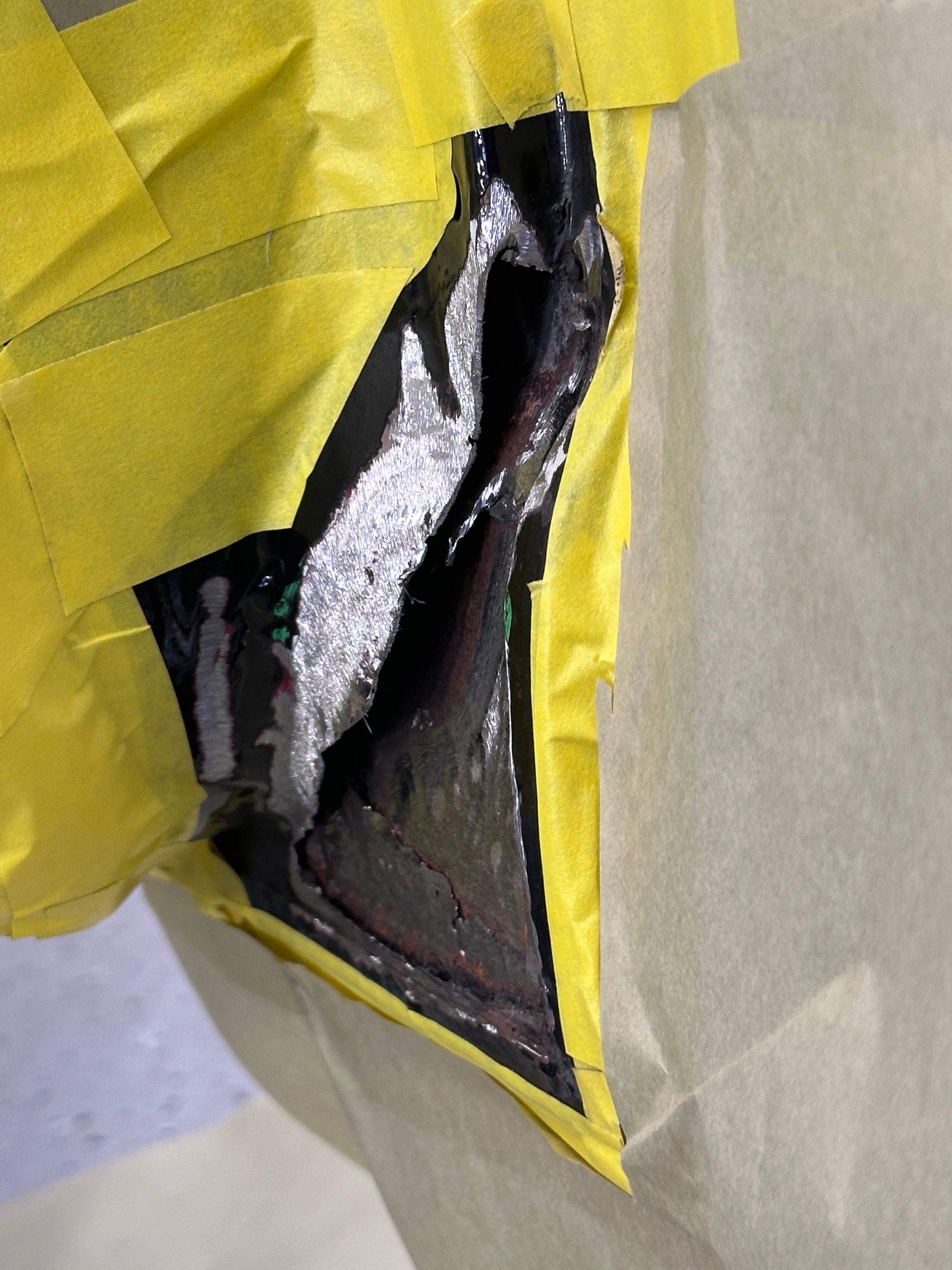 A piece of yellow tape is covering a hole in a piece of paper