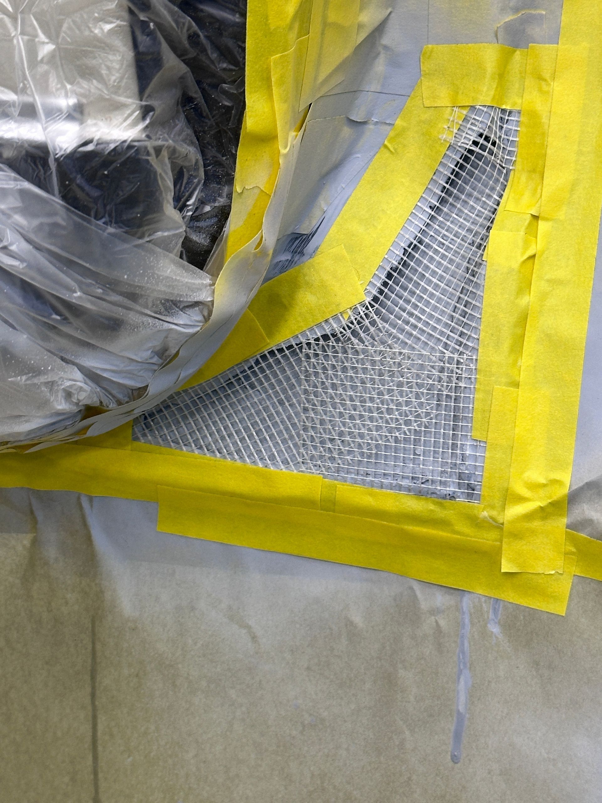 A piece of metal is taped to a plastic bag with yellow tape