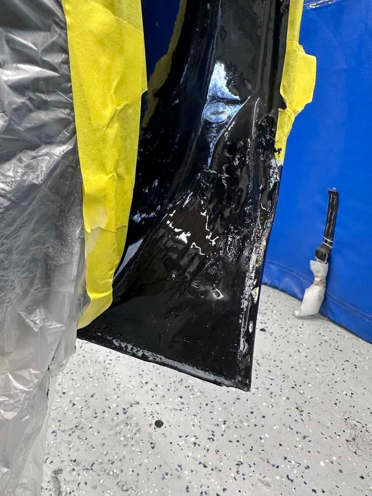 A piece of black plastic is sitting on the floor next to a blue wall.