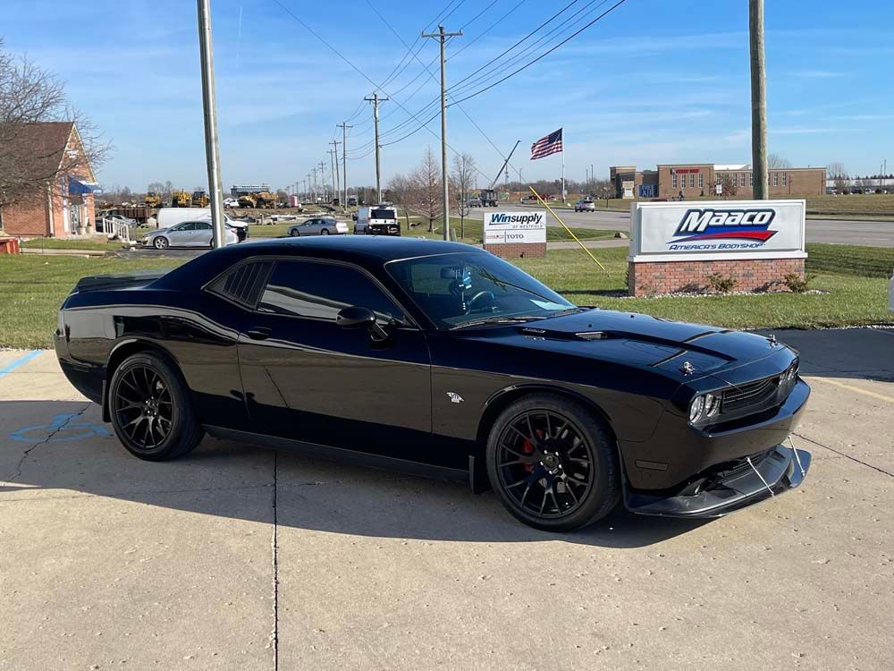 A black dodge challenger is parked in a parking lot.