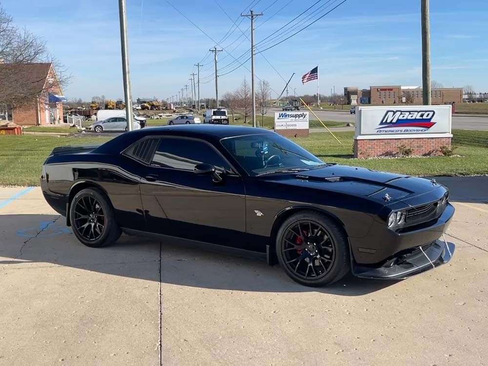 A black dodge challenger is parked in a parking lot.