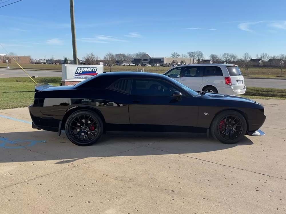 A black dodge challenger is parked in a parking lot.