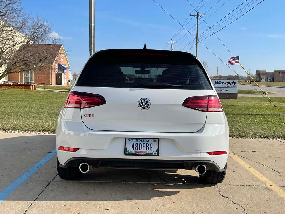 A white volkswagen golf is parked in a parking lot.