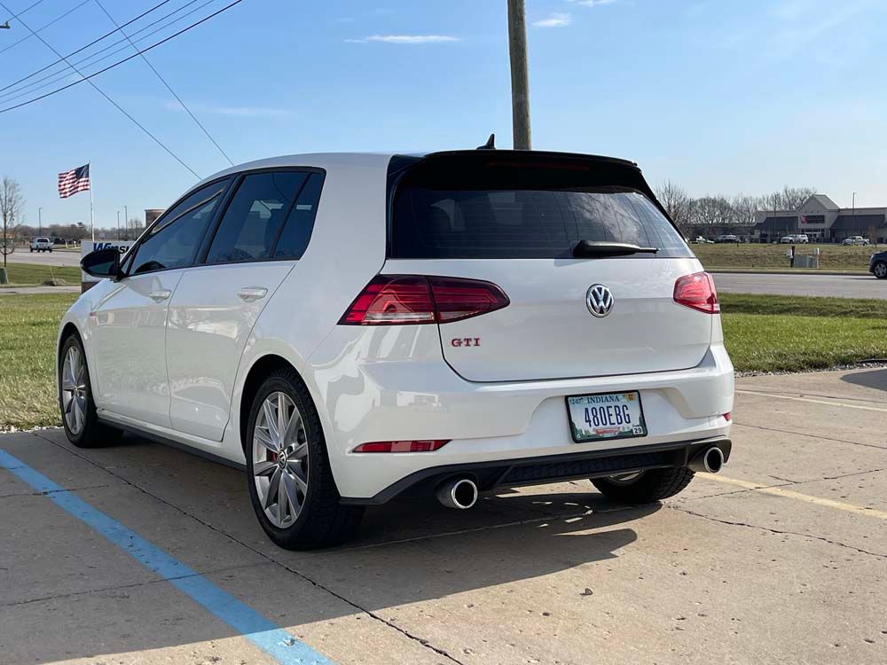 A white volkswagen golf is parked in a parking lot.
