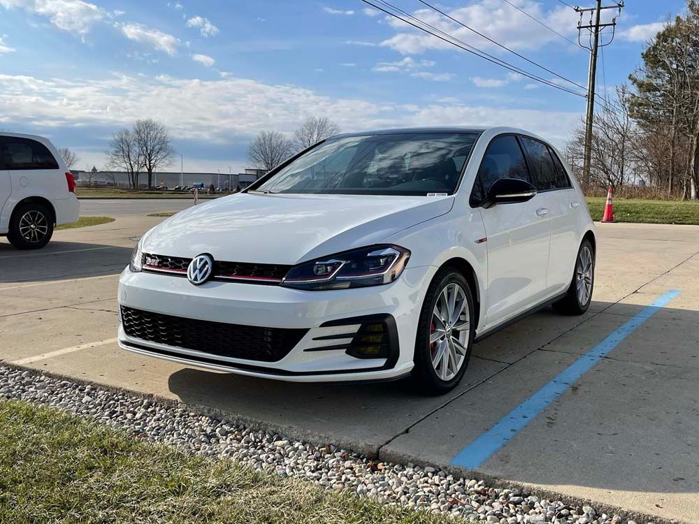 A white volkswagen golf gti is parked in a parking lot.