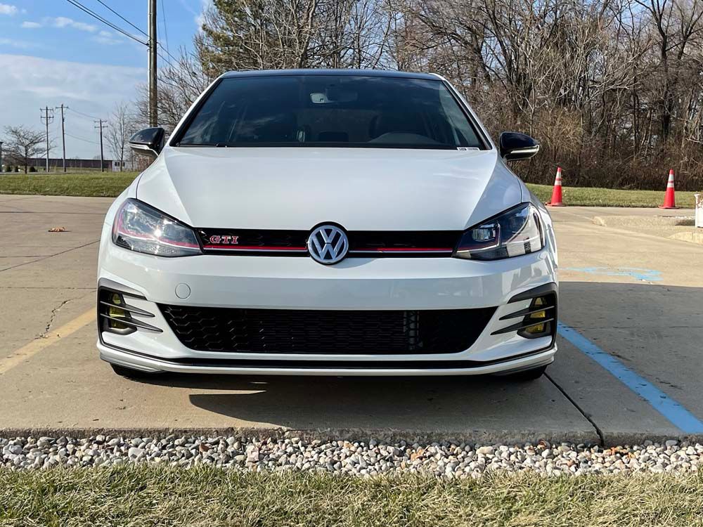 A white volkswagen golf gti is parked in a parking lot.