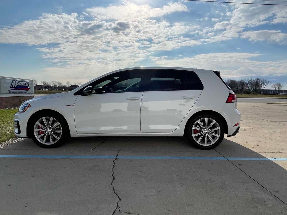 A white volkswagen golf is parked in a parking lot.