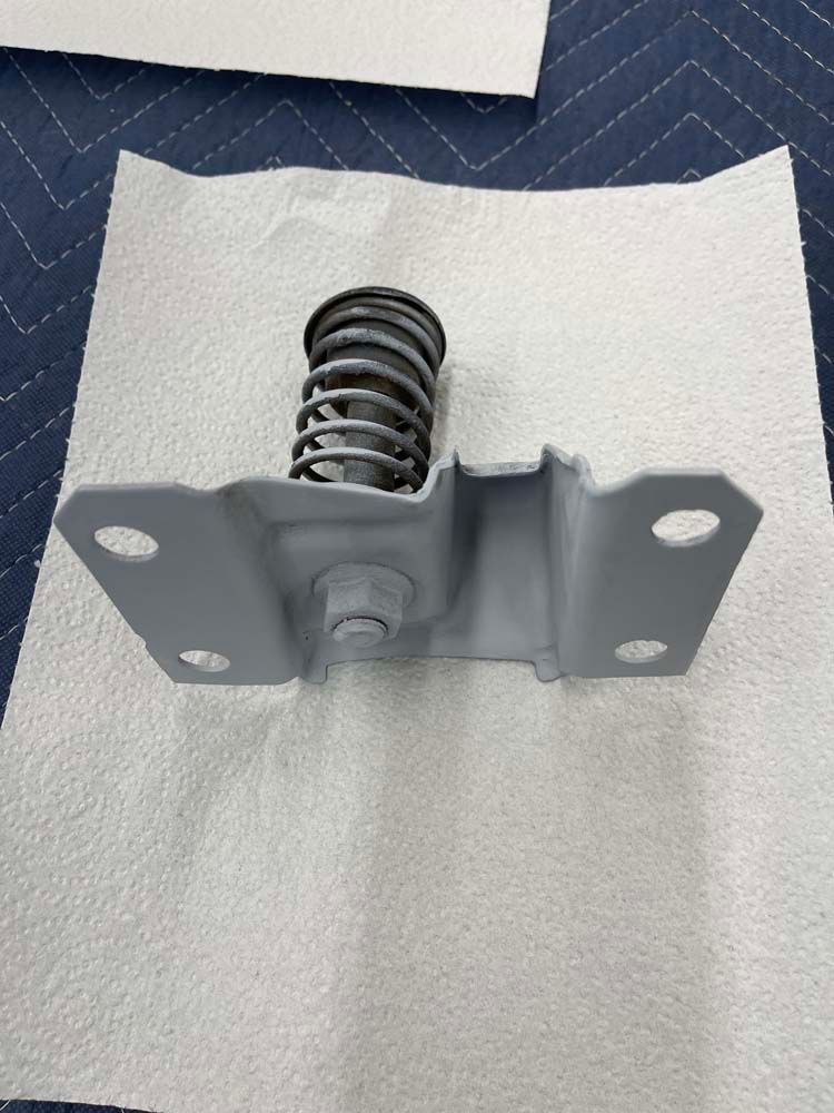 A piece of metal with a spring on it is sitting on a piece of paper towel.