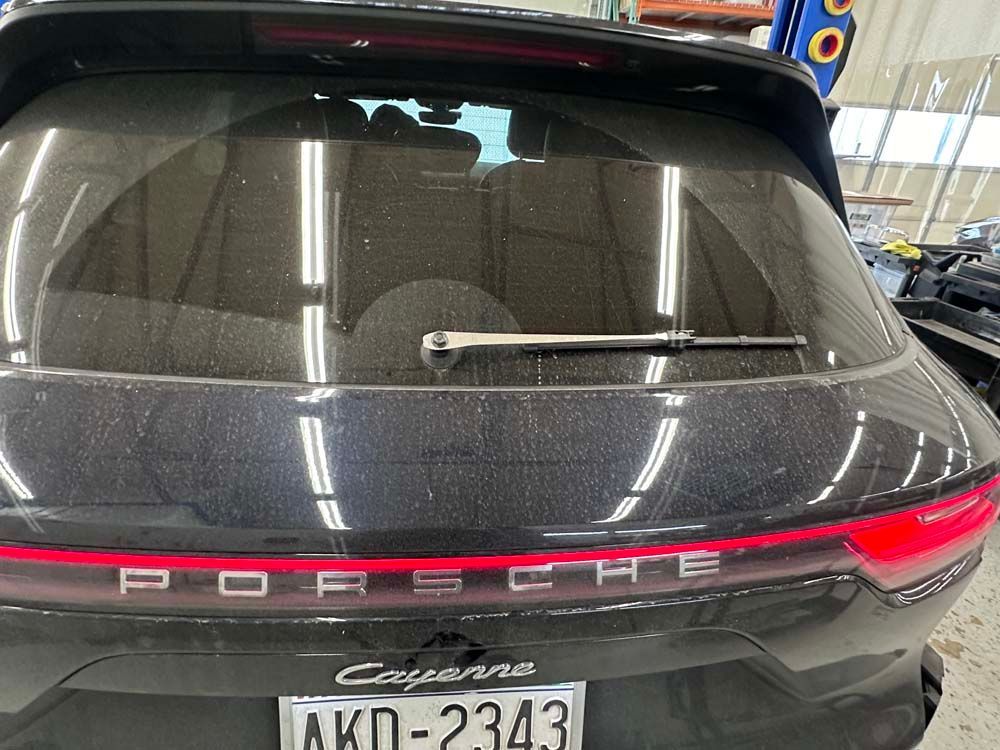 A black porsche cayenne is parked in a garage