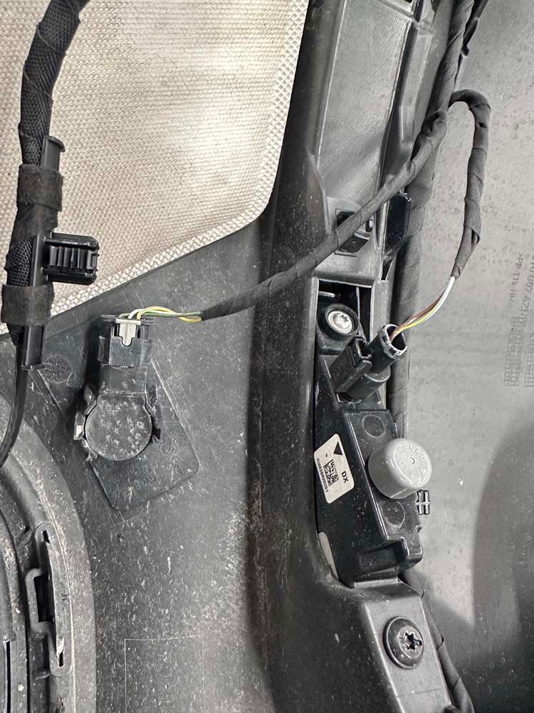 A close up of a bumper with wires coming out of it.