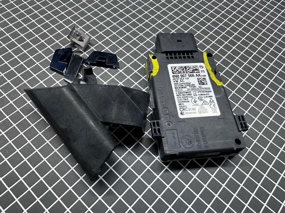 A remote control is sitting on a checkered table next to a key.