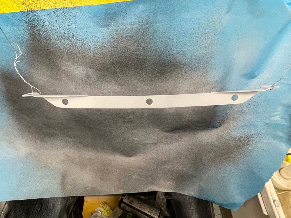 A piece of metal is sitting on top of a piece of paper covered in spray paint.