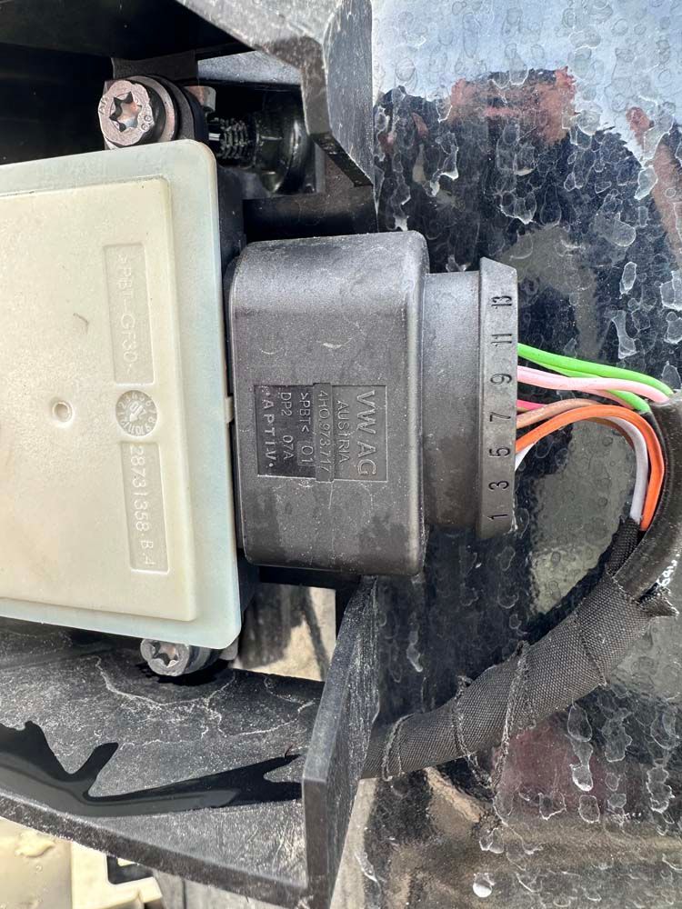 A close up of a connector on a car with wires coming out of it.