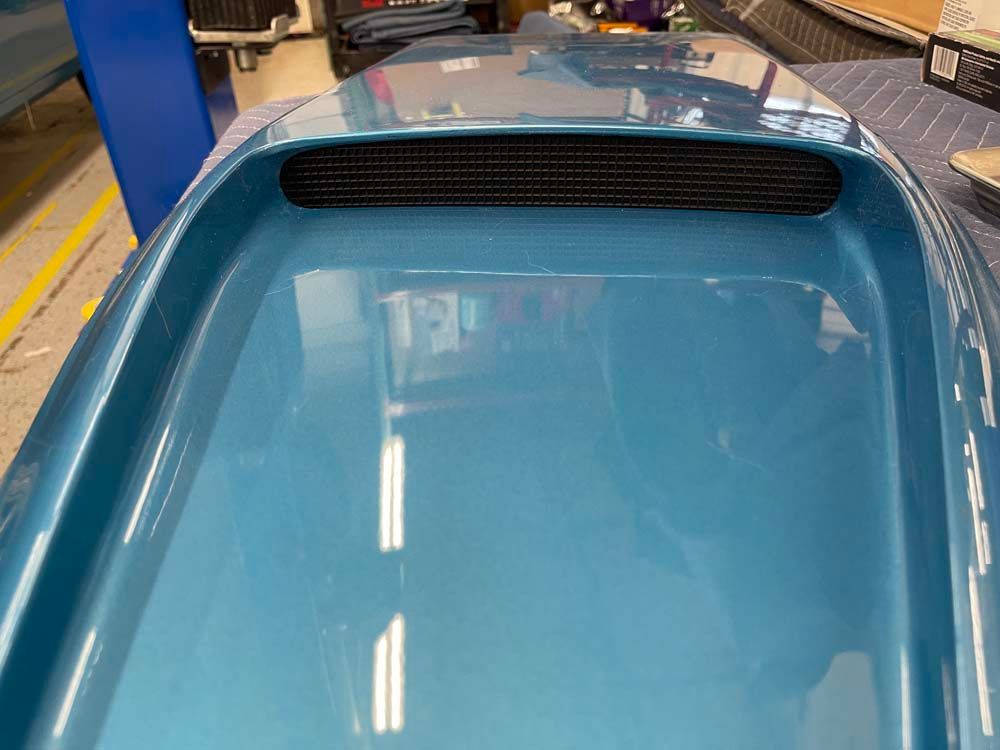 The hood of a blue car is sitting on a table.