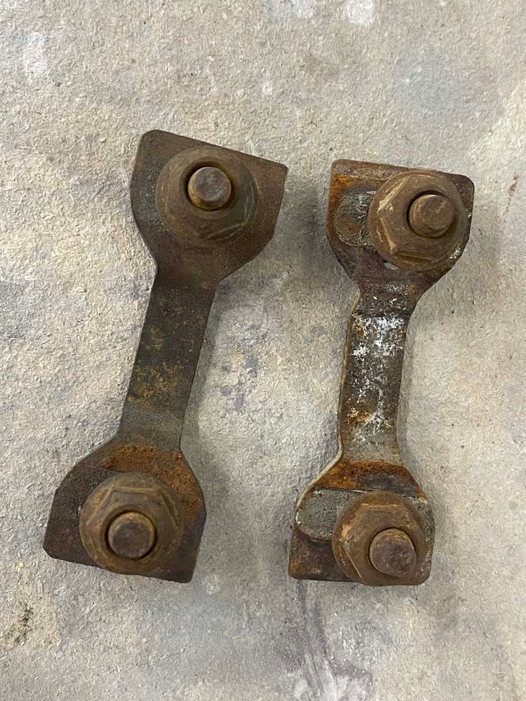 A pair of rusty metal pieces sitting on top of a concrete surface.