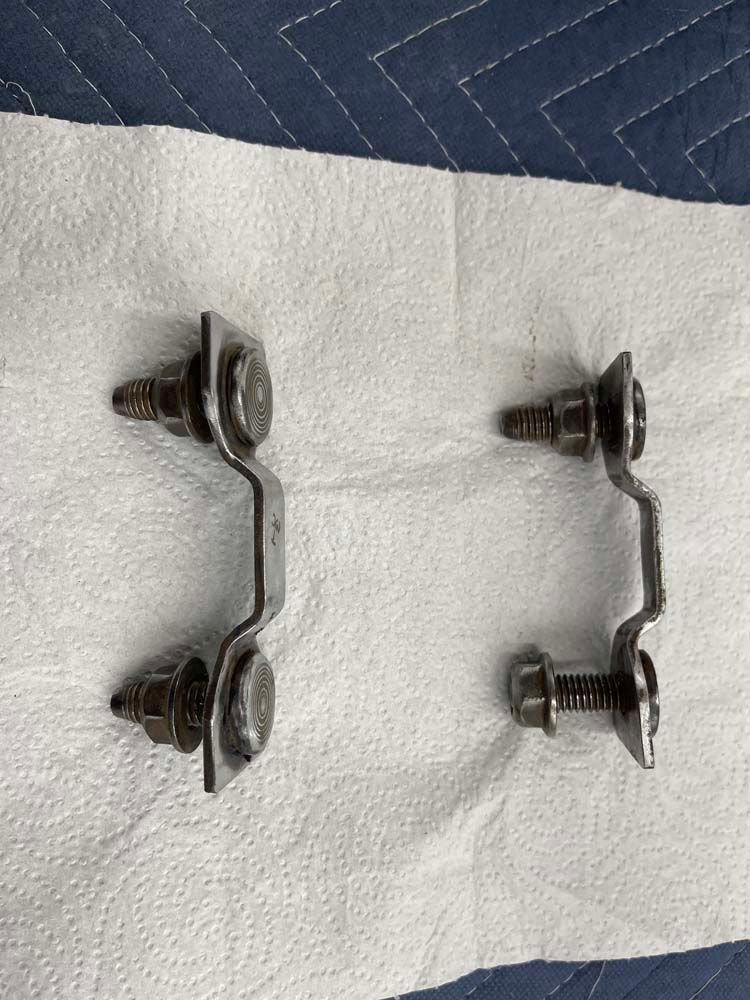 A pair of metal brackets sitting on top of a piece of paper towel.