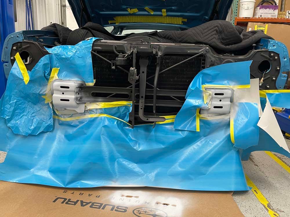 A subaru car is being painted in a garage