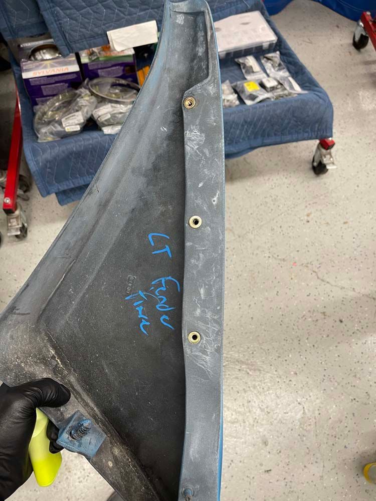 A person is holding a spray bottle next to a piece of metal.