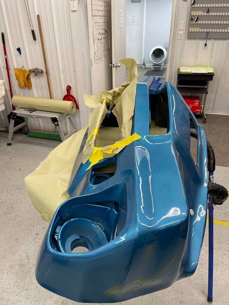 A blue car is being painted in a garage.