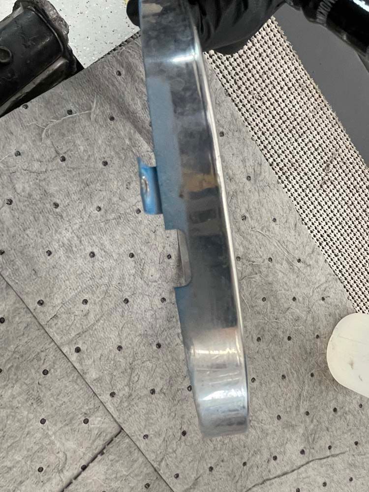 A person is holding a piece of metal on a table.