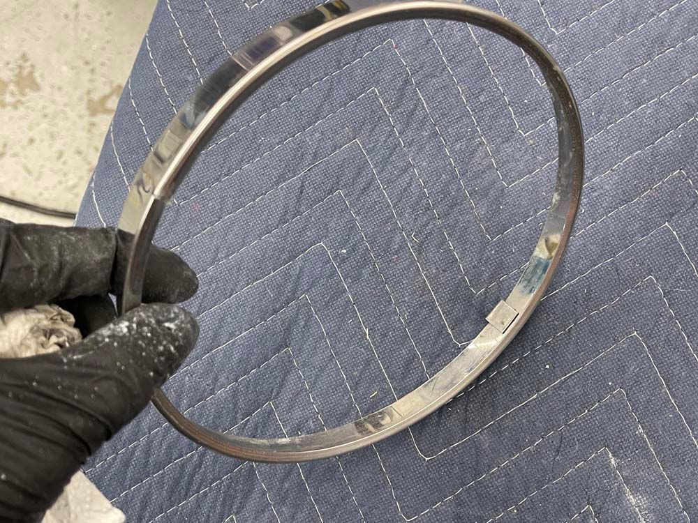 A person is holding a metal ring on a blue blanket.