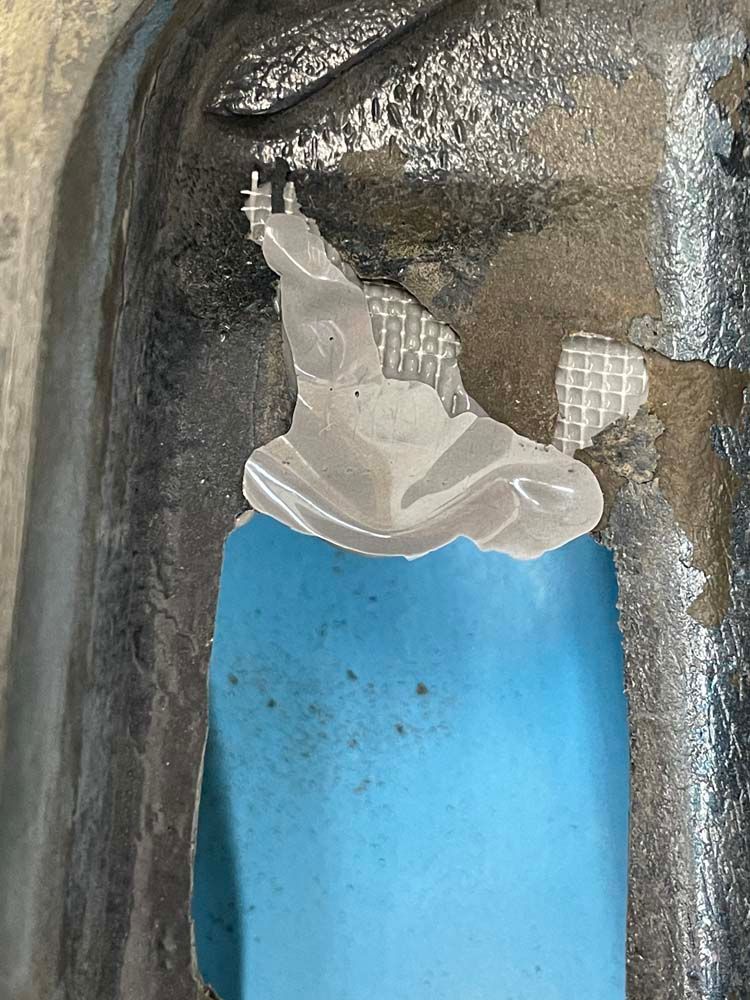 A piece of plastic is sticking out of a hole in a metal pipe.