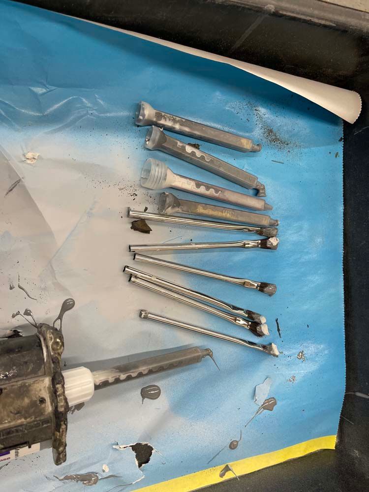 A bunch of screws are laying on a blue surface.