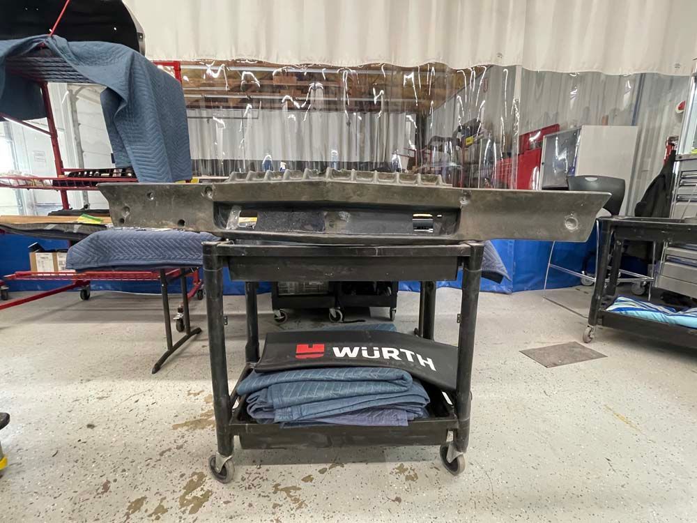 A large piece of metal is sitting on top of a cart in a garage.
