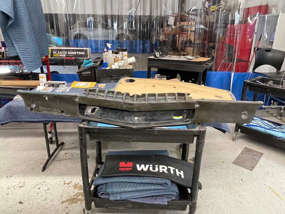 A bumper is sitting on top of a cart in a garage.