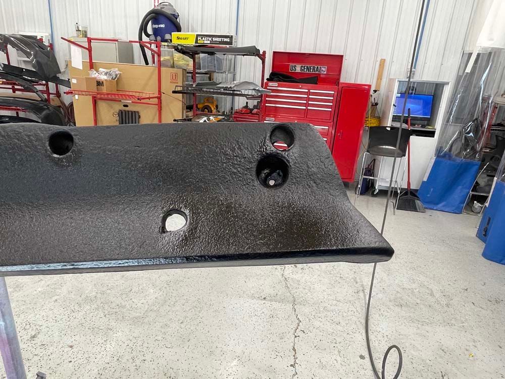 A black piece of metal is sitting on a table in a garage.