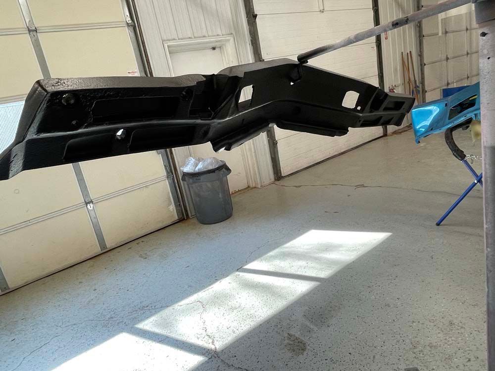 A black piece of metal is hanging from a metal pole in a garage.