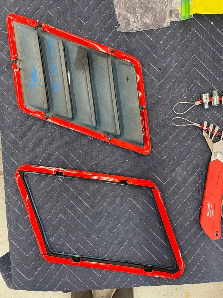 A pair of red fender vents are sitting on a table next to a pair of pliers.