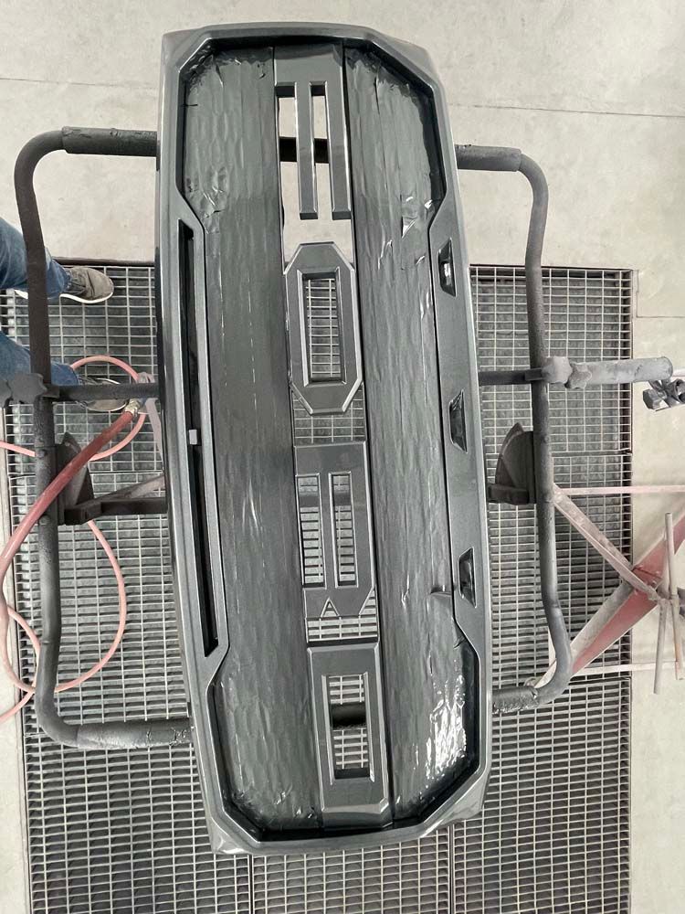 A gray object is sitting on a metal grid on the floor.