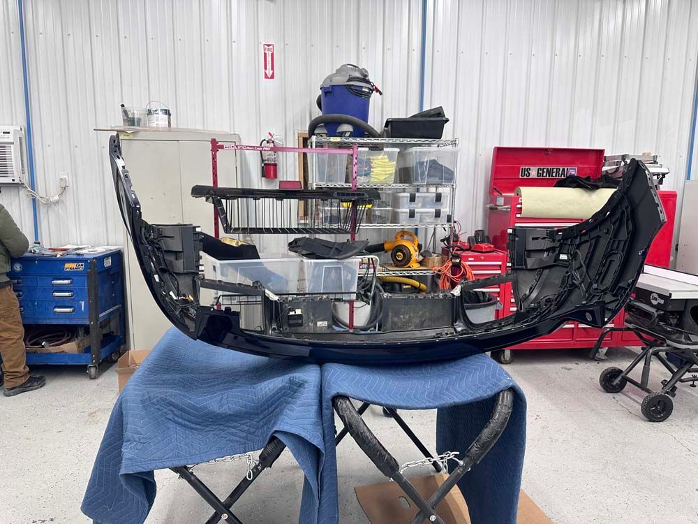 A bumper is sitting on top of a blue blanket in a garage.