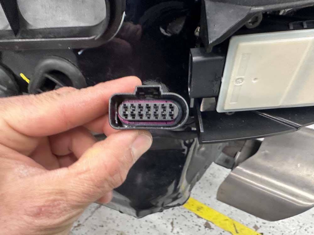 A person is holding a black connector in their hand