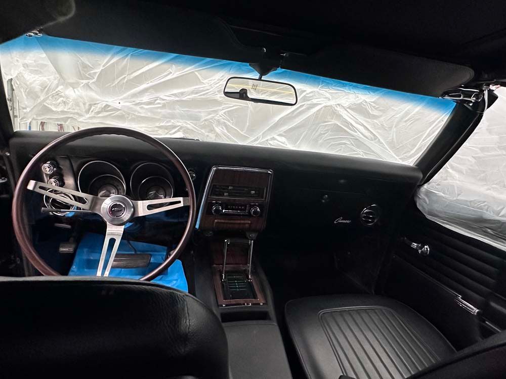 The interior of a car with a steering wheel and a rear view mirror.