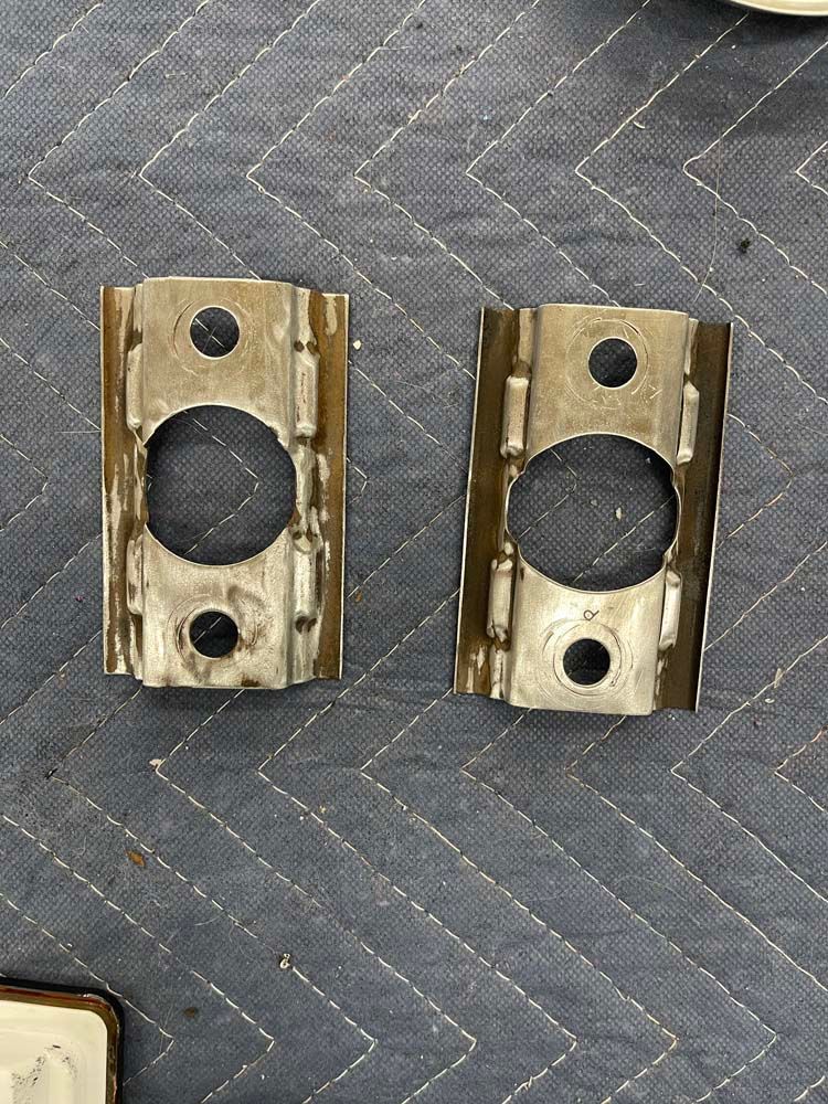 A pair of metal brackets with holes in them are sitting on a table.