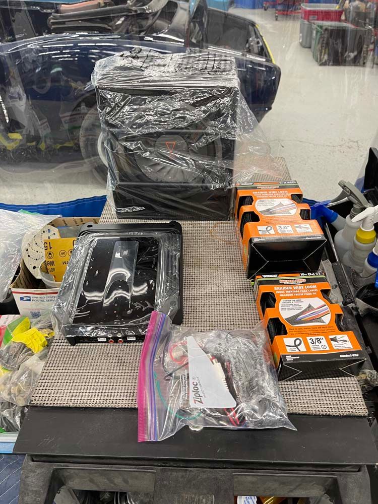 A table with a lot of items on it and a car in the background.