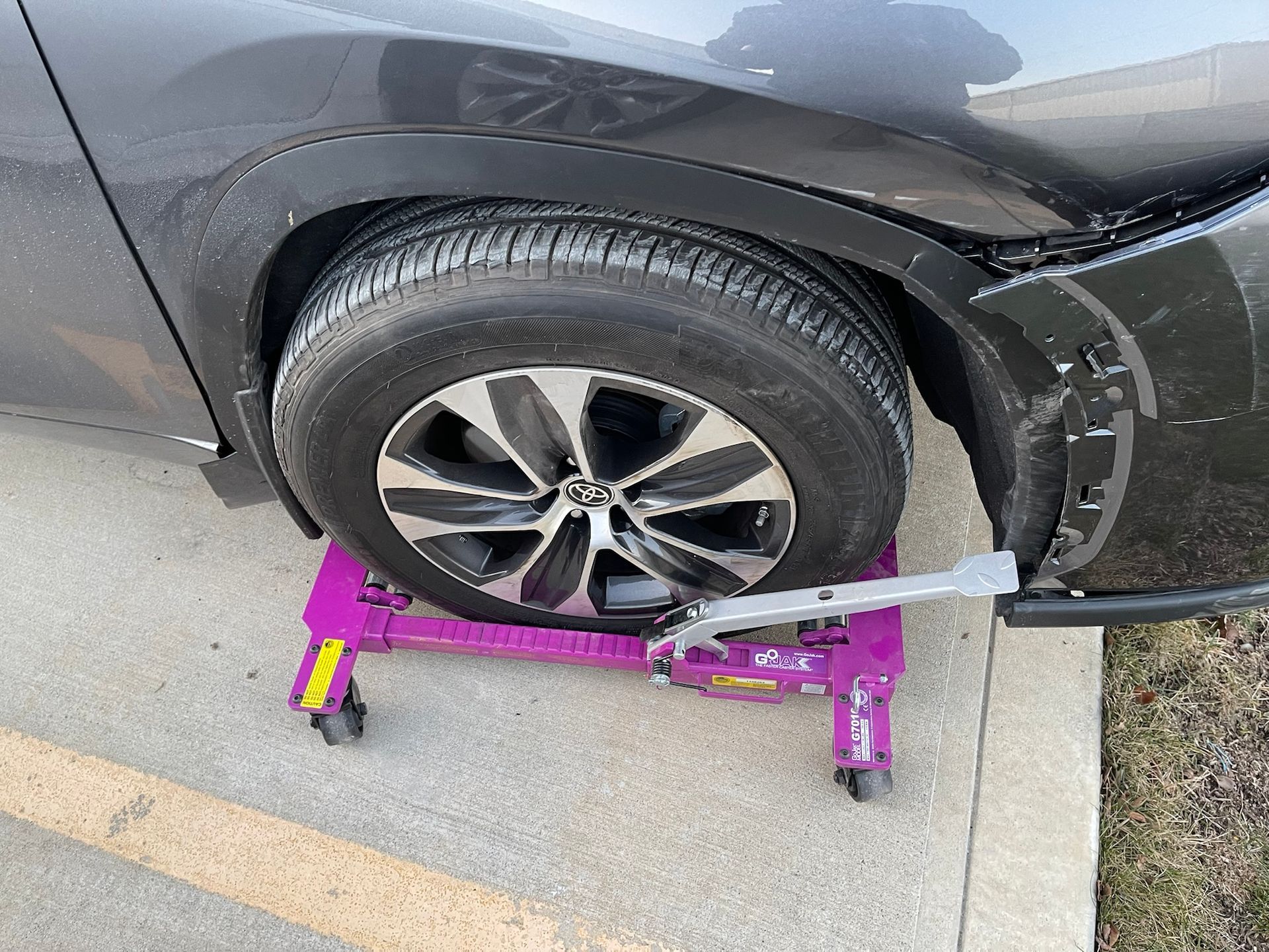 A car is being towed by a purple tow dolly.