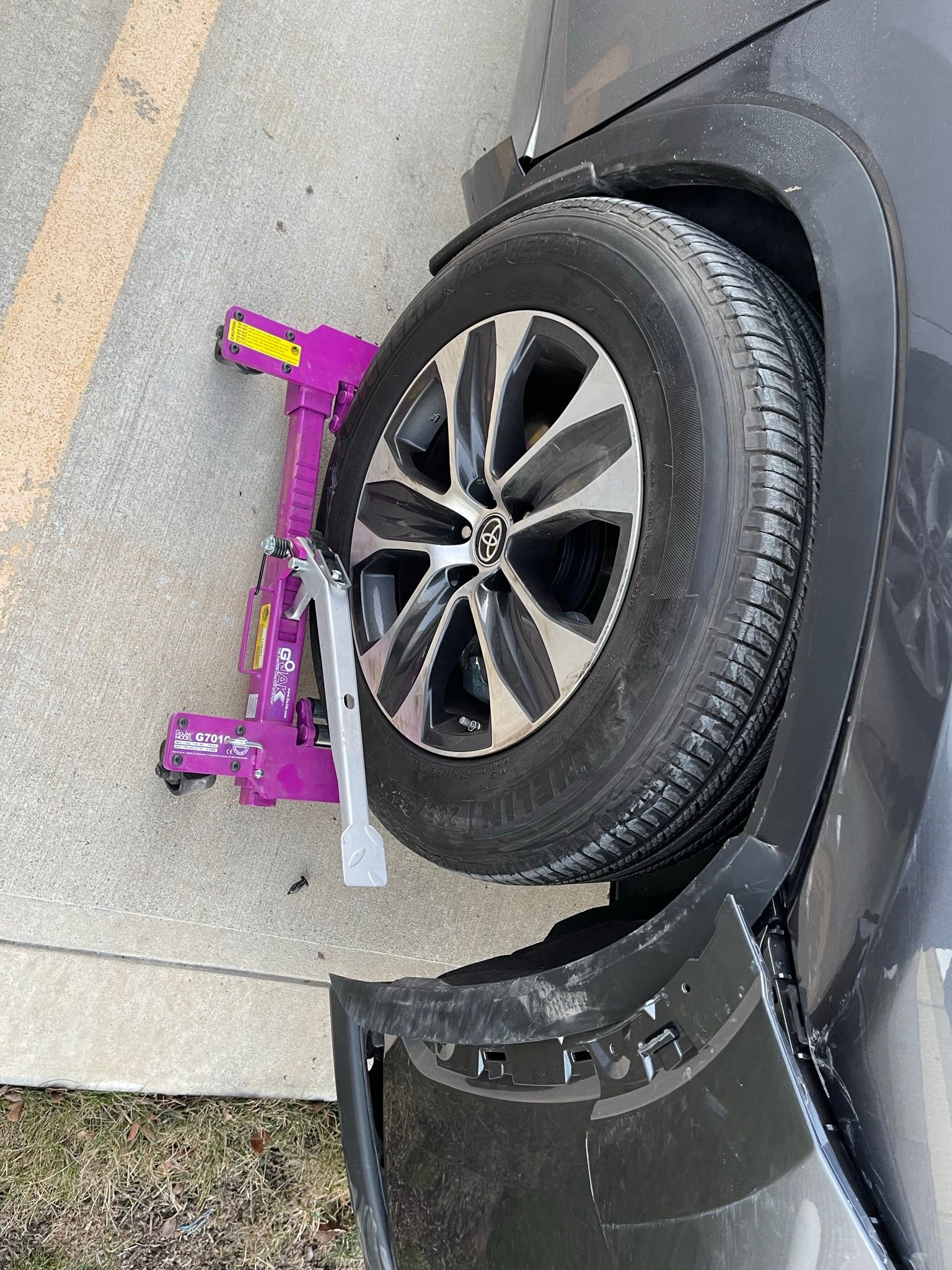 A purple wheel clamp is sitting on the side of a car.