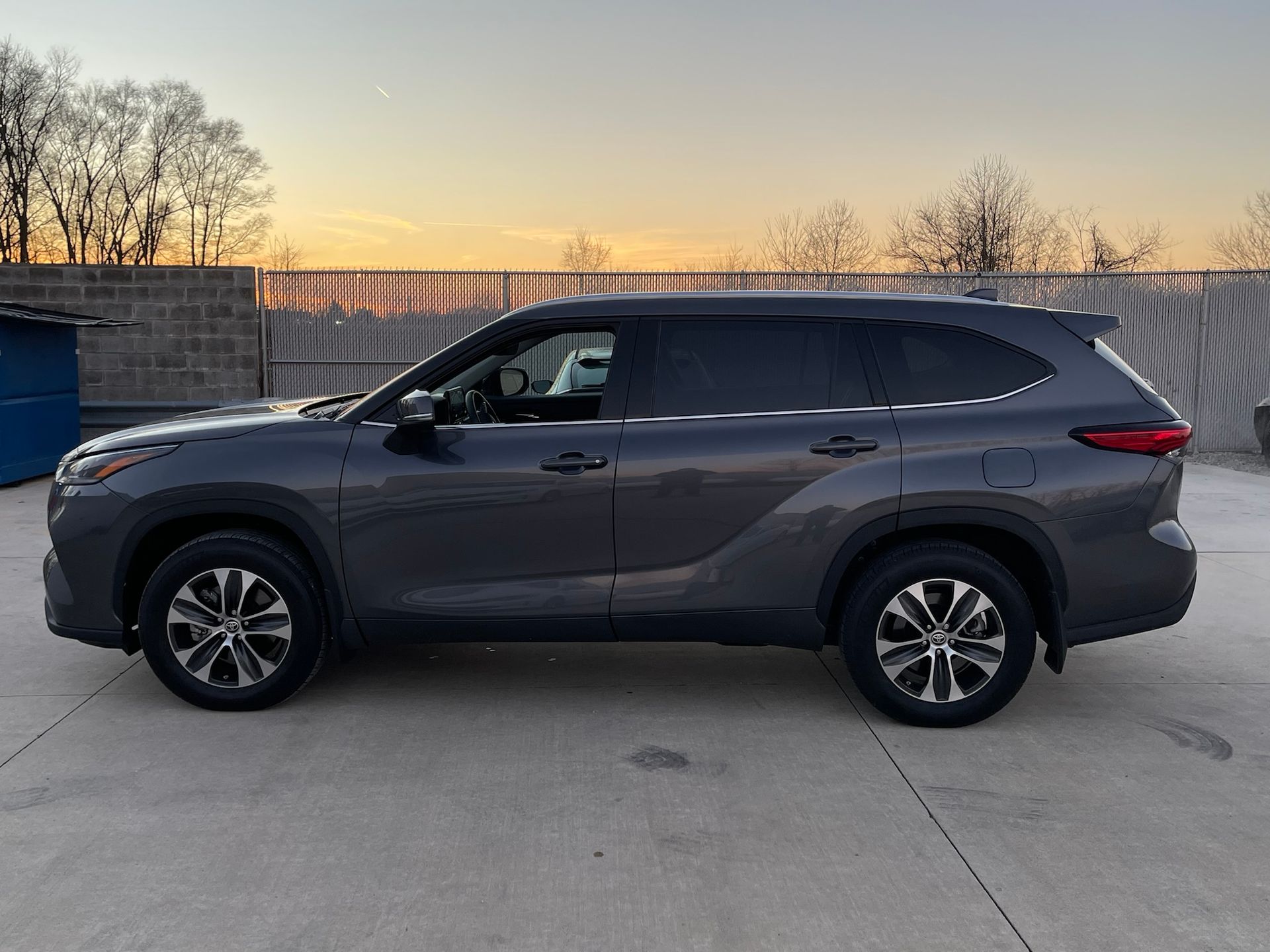 A toyota highlander is parked in a parking lot at sunset.
