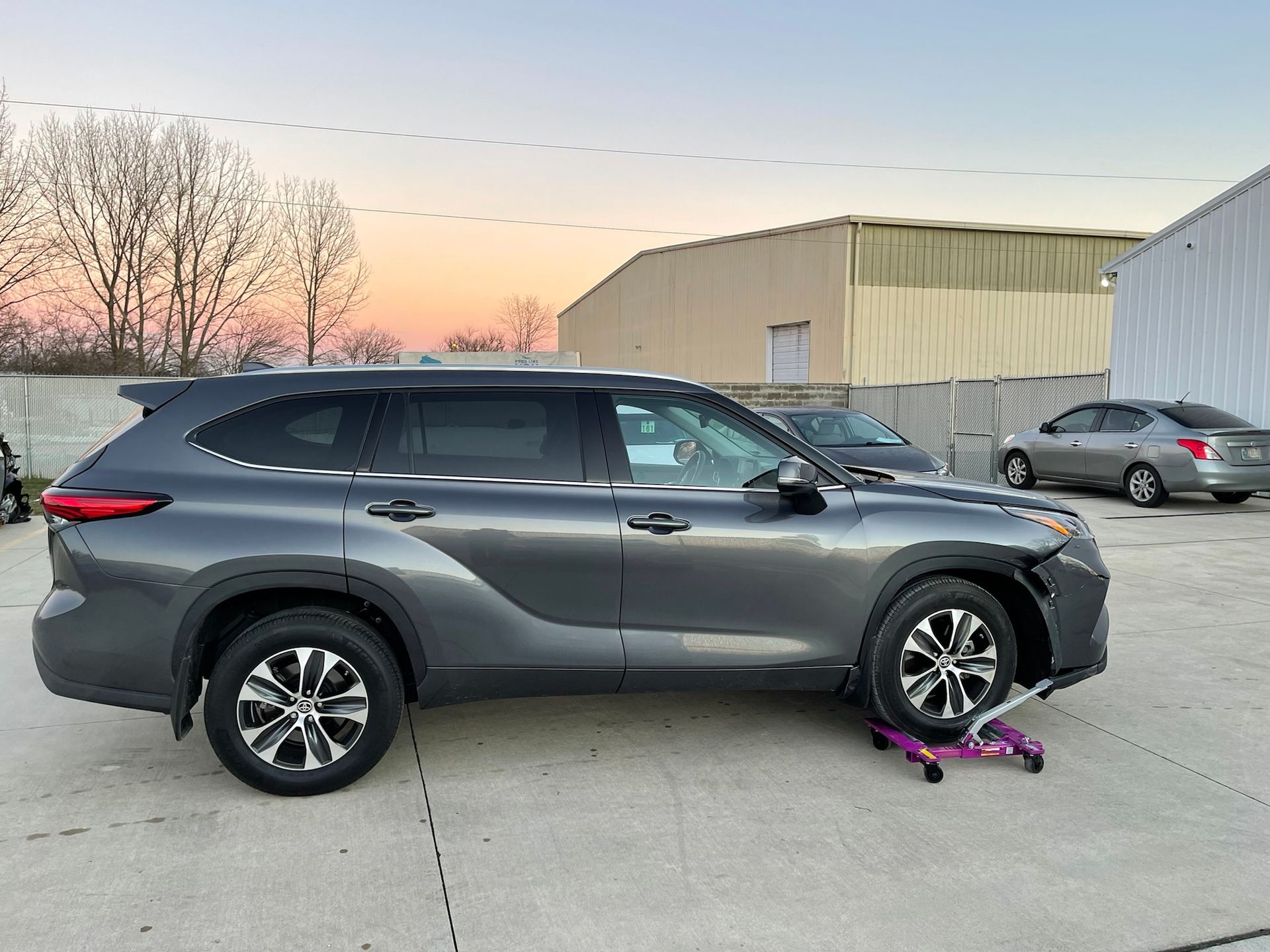 A toyota highlander is parked in a parking lot with a flat tire.