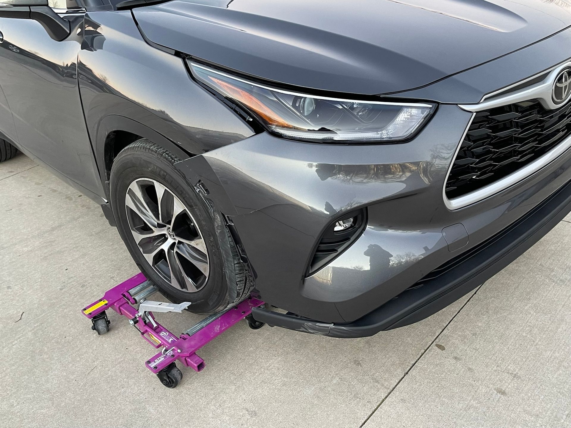 A toyota highlander is sitting on a purple wheel jack.