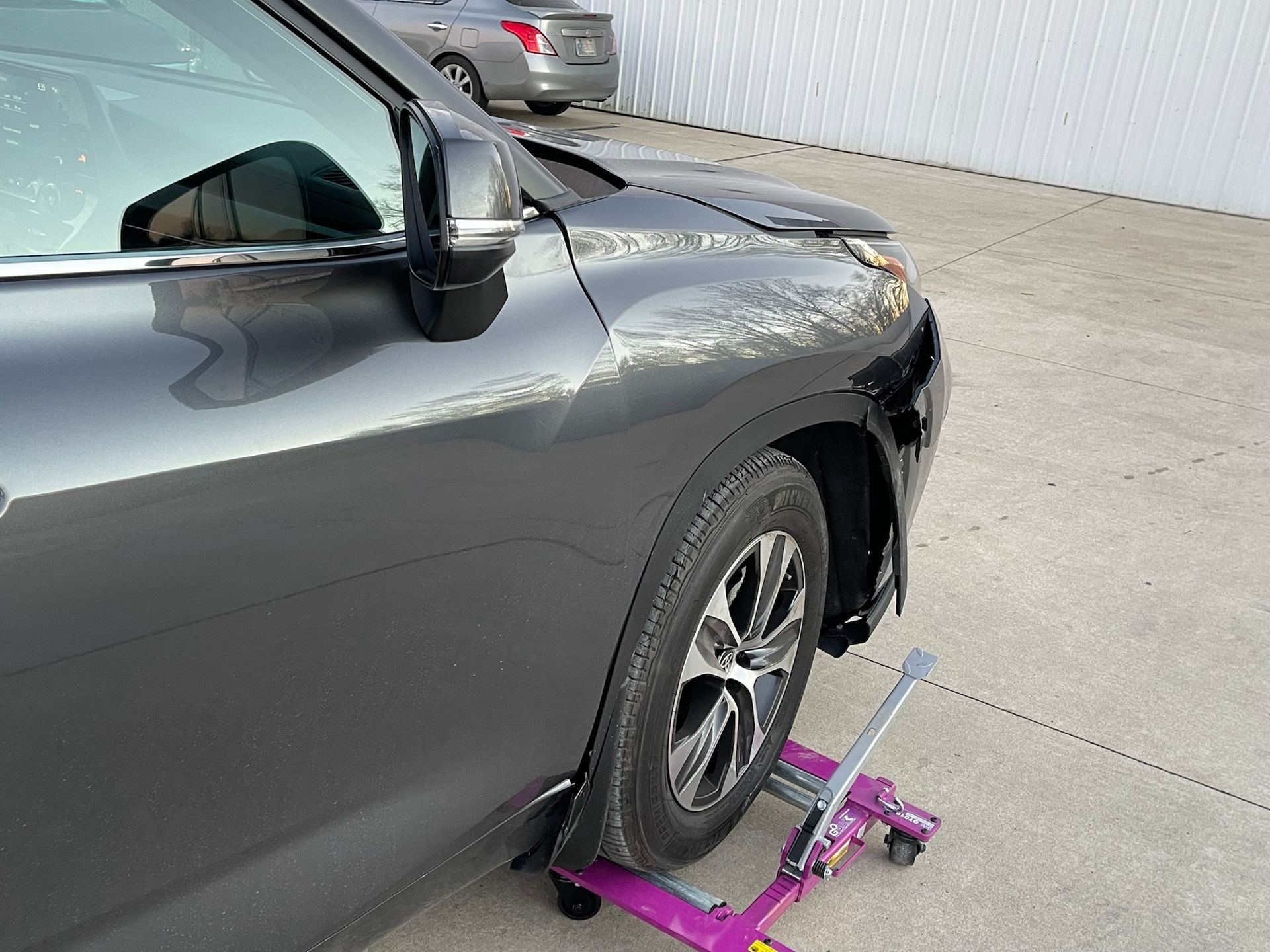 A car is sitting on a purple wheel jack.