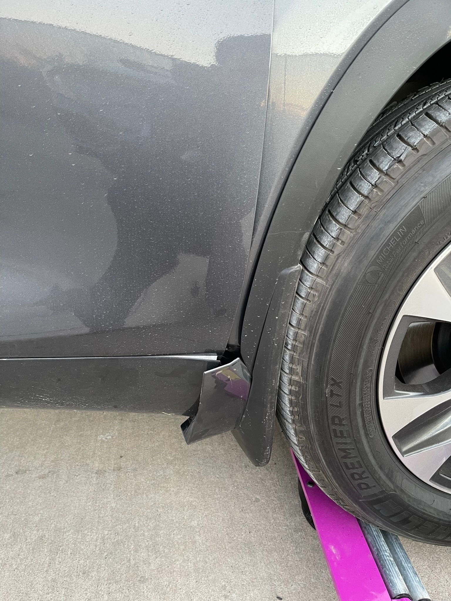 A close up of a car tire with a tow strap attached to it.