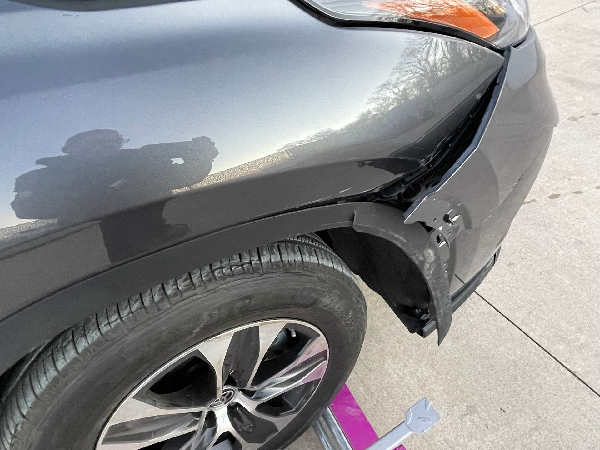 A car with a damaged fender is sitting on a tow truck.