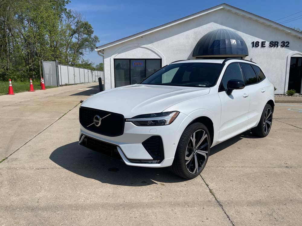 A white volvo xc60 is parked in front of a white building.